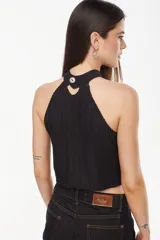 Top de punto estilo halter, color crudo, con cuello alto ajustado, diseño sin mangas y corte corto.