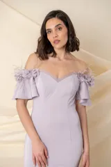 Vestido largo de crepé de seda color lila, modelo entallado con falda con vuelo. Mangas cortas con apliques de flores de tela, organza y plumas.