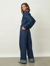 Jean de mezclilla azul oscuro, tiro alto, corte ancho y pierna recta muy amplia, con puños doblados que muestran el interior más claro.