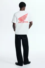 Remera de algodón color blanco con cuello redondo y estampado frontal con el logo de Honda en color rojo.