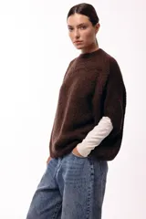 Sweater de tejido de punto grueso con silueta amplia y mangas 3/4. Presenta un diseño de calce relajado con cuello redondo y textura voluminosa.