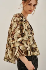Camisa de lurex con estampado animal print en tonos dorados y marrones, con escote en V profundo y mangas amplias con volados. Incluye forro interior.