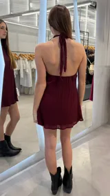Vestido corto bordó con diseño plisado, escote halter y silueta fluida.