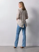 Camisa color beige de tencel, marca Hester & Orchand, con cuello con solapa, escote en V, abertura central con botones y bolsillos delanteros. Las mangas son largas y regulables con presilla y botón.