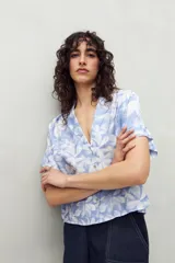 Camisa estampada de manga corta con cuello solapa y botones de nácar al frente, confeccionada en un tejido liviano de sutil textura que aporta movimiento y frescura.