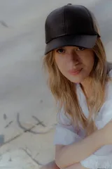 Gorra de béisbol negra de cuero sintético con hebilla metálica ajustable en la parte posterior.