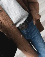 Cinto de cuero negro con hebilla hexagonal metálica de estilo vintage, decorada con un diseño floral y central de esferas.