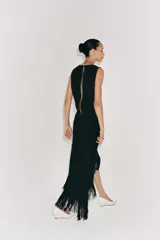 Vestido midi de Zara Woman Collection color negro, sin mangas, con cuello redondo y espalda abierta. Presenta un diseño asimétrico en el bajo adornado con flecos a tono, y cierre trasero con cremallera y botón.