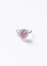 Anillo de plata 925 con piedra central zirconia de color rosado en corte redondo, rodeada por un halo de pequeñas zirconias y engaste pavé en los hombros del aro.