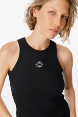 Musculosa de tejido acanalado color negro, con cuello redondo y diseño ajustado al cuerpo. Presenta un pequeño bordado decorativo en el centro del pecho.
