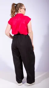 Pantalón parachute negro de corte ancho, con cintura alta ajustable con cordón, bolsillos laterales y bolsillos cargo en las piernas.