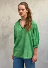 Blusa verde de algodón plumeti con escote en V con volados y mangas 3/4 abullonadas con puños elásticos.