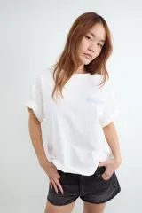 Remera boxy blanca de manga corta, con cuello redondo y estampa minimalista en el pecho, de corte relajado.