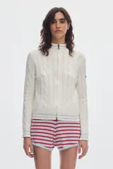 Cardigan de punto color marfil con cierre frontal completo, cuello alto y detalles de rayas en contraste en cuello, puños y ruedo. Presenta diseño de ochos verticales.