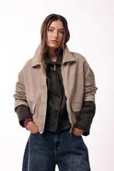 Campera corta color marrón, con cuello alto estructurado, cierre frontal y bolsillos delanteros con solapa. Presenta puños y cuello en tejido acanalado, con un diseño de corte recto y minimalista.