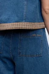 Pantalón de jean azul de corte ancho y tiro alto, con costuras verticales frontales que estilizan la silueta y diseño de pierna recta.