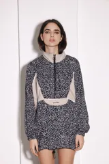 Buzo tipo canguro con cierre frontal parcial, cuello alto y diseño combinado con estampado animal print y paneles en color beige. Cuenta con puños elásticos y cordón ajustable en el ruedo.