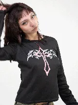 Remera crop de manga larga en color negro, con ajuste slim fit. Presenta un estampado frontal de una cruz con alas en tonos blanco y rosado.