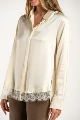 Camisa de satén color arena, de corte clásico con cuello camisero, manga larga con puños abotonados y detalle de encaje en el ruedo.