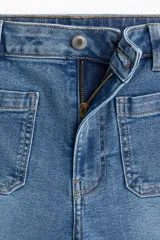 Jean de denim azul claro con ligero efecto desgastado, tiro alto y pierna ancha. Presenta bolsillos parche cuadrados en la parte trasera y bolsillos delanteros con solapa. El bajo es ancho y está diseñado para apilarse.