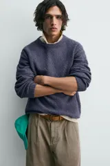 Jersey de hombre de corte relajado, color azul oscuro o morado apagado, con textura rizada (bouclé) y cuello redondo.