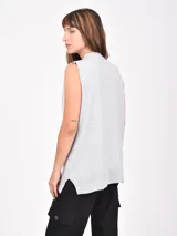 Chaleco de tejido de punto color gris claro, sin mangas, con escote en V profundo y cuello acanalado.