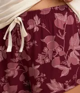 Conjunto de pijama americano corto confeccionado en viscosa. Son dos prendas: Blusa lisa color crema con manga corta, cuello polo y botones; y short color borgoña con cintura elástica y estampa floral.