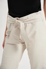 Pantalón de cuero color beige, de corte recto, con cintura alta y lazo para ajustar.