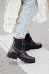 Bota tipo chelsea de cuero color marrón oscuro, con paneles laterales elásticos y suela track robusta con plataforma.