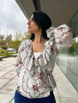 Blusa estampada con cuello en V, mangas largas abullonadas y corte a la cintura.