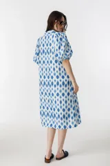 Vestido midi de lino con estampado floral azul y blanco, cuello clásico, mangas abullonadas hasta el codo y cierre frontal con botones de nácar.