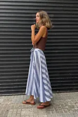 Falda larga confeccionada en 100% algodón con estampado de rayas en azul y blanco. Presenta un diseño cruzado con lazo ajustable en la cintura y caída fluida.