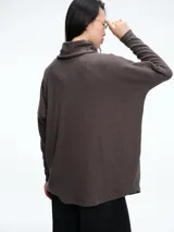 Sweater de silueta amplia y corte holgado, confeccionado en tejido de punto color gris oscuro. Presenta cuello polera, mangas largas con ajuste en los puños y diseño contemporáneo.