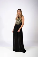 Vestido largo de fiesta con cuerpo superior decorado con apliques geométricos dorados y falda fluida de gasa negra con transparencia.