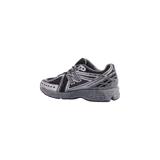 Championes New Balance modelo 1906R, color gris y negro, con diseño técnico inspirando en el running de los años 2000, parte superior de malla y superposiciones sintéticas, con logo "N" lateral y suela amortiguada con tecnología N-ergy.