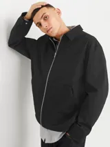 Campera estilo worker de color negro, con cierre frontal de cremallera, cuello clásico y dos bolsillos frontales. Presenta un diseño de corte recto y tejido liviano.