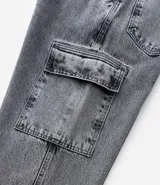 Pantalón de jean modelo baggy con bolsillos cargo laterales, cintura con trabillas y cierre frontal con botón y cremallera.