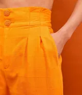 Pantalón recto de tiro alto color naranja, con doble botonadura, pinzas y trabillas en la cintura.