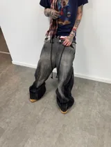 Jean de corte amplio en color negro con efecto acid wash. Presenta cierres laterales metálicos que permiten ajustar la silueta entre corte recto, oxford o baggy. Incluye una estampa gráfica de gran tamaño en la parte trasera con detalles bordados, bolsillos amplios y una etiqueta de cuero legítimo en la cintura.
