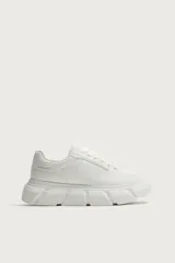 Zapatilla de estilo urbano con suela de plataforma voluminosa y diseño irregular. Presenta un diseño de paneles en la parte superior y cierre mediante cordones.