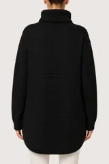 Polera de punto color negro con cuello alto, diseño de corte holgado y ruedo asimétrico con detalle de costura frontal.