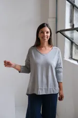 Remera de algodón gris con cuello en V, mangas largas y corte holgado con ruedo asimétrico.