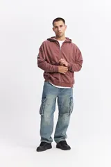 Campera con capucha de algodón con efecto acid wash, corte oversize y estampa gráfica en la espalda con la frase 'WE ARE NOT HERE TO PLAY GAMES' y logo de la marca Mistral.