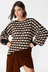 Sweater de punto con diseño geométrico de ondas en colores negro, marrón y crema. Presenta cuello redondo, mangas largas abullonadas con puños acanalados en color negro y un corte holgado.