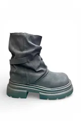 Bota de caña media color negro, con diseño fruncido, suela flatform chunky texturizada y tira decorativa con hebilla en el lateral.