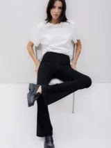 Pantalón de jean negro de tiro alto, corte ajustado en caderas y muslos, con pierna acampanada.