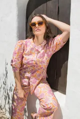 Camisa de lino con estampado floral en tonos rosados y naranjas, de corte recto, cuello mao y cierre frontal con botones. Presenta mangas al codo con frunces en los hombros.
