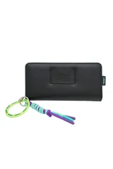 Billetera negra con cierre, llavero de cinta con inscripción Trendy y detalle de cordones trenzados en colores violeta y celeste.