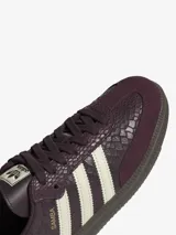 Championes Adidas Samba OG de caña baja, con diseño clásico de puntera en forma de T y tres bandas laterales dentadas. Presenta un empeine de cuero con estampado texturizado en color bordó y detalles en crema, sobre una suela de goma oscura.