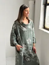 Vestido largo color verde militar con estampado floral, cuello drapeado y mangas largas de corte holgado.